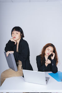 Young woman looking away while sitting on laptop