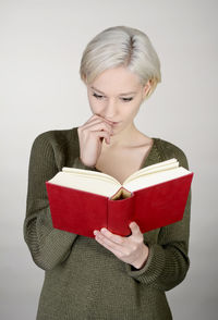 Young woman reading book against white background