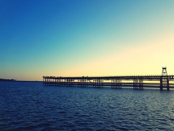 Pier over sea against clear sky during sunset