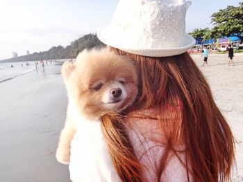 Close-up of woman carrying dog at beach