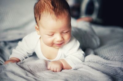 Cute baby boy lying on bed at home