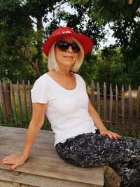 Portrait of woman wearing hat while sitting on table against trees