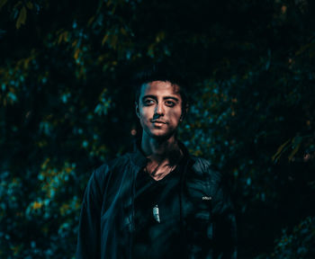 Portrait of young man standing against trees