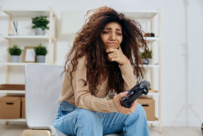 Woman playing video game through joystick at home