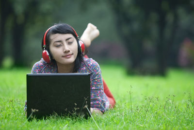 Smiling woman listening music at lawn