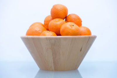 Close-up of oranges in bowl against white background