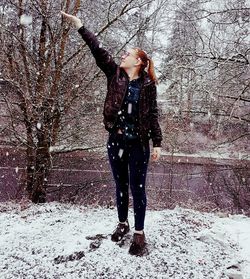 Full length of woman standing in snow covered forest