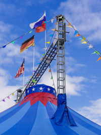 Low angle view of flags on tent against sky