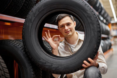 Portrait of man holding tire at store