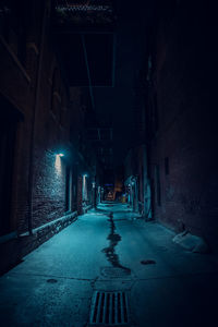 Empty road amidst illuminated buildings at night