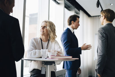 Female entrepreneur talking to colleague while coworker standing in background at workplace