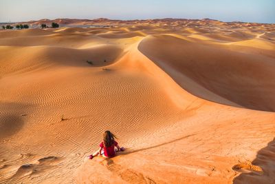 Rear view of girl sitting at desert