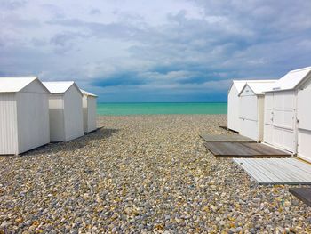 Beach huts by sea against sky