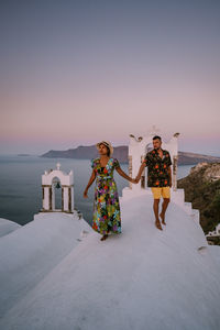 People standing by sea against clear sky