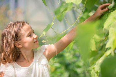 Side view of young woman holding plant