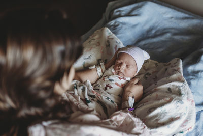 Overhead view of mother holding newborn boy with hat in hospital bed