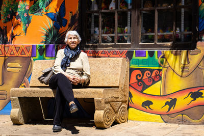 Senior woman tourist sitting on a bench at the beautiful streets of the city of raquira. 