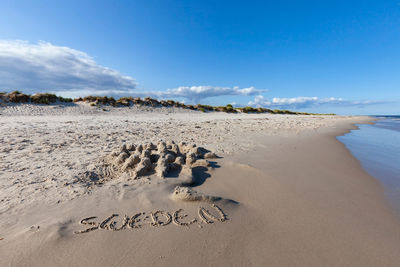 Text on beach against sky