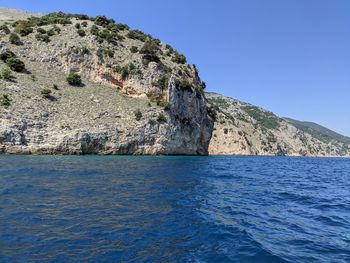 Rock formation in sea against clear blue sky