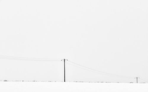 Low angle view of electricity pylon against sky during winter