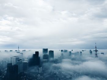 Aerial view of cityscape covered with fog against sky during dusk