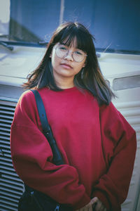 Asian teenager wearing red sweater standing outdoor