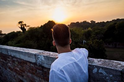 Rear view of man looking at mountains against sky