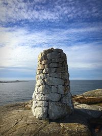 Stone stack on rock by sea against sky
