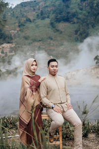 Portrait of young couple standing against mountain