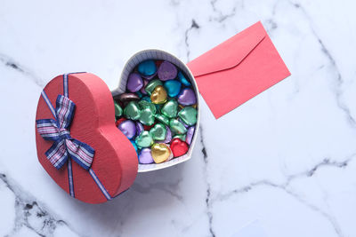 Heart shape gift box, candy and letter on tiles background .