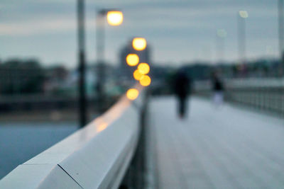 People walking on illuminated street at dusk