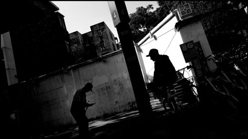 Silhouette men standing on street amidst buildings in city
