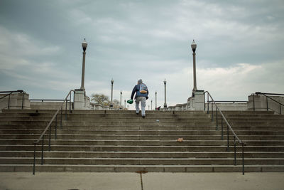 Low angle view of man on staircase against cloudy sky