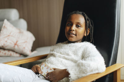 Portrait of girl with smart phone sitting on armchair at home