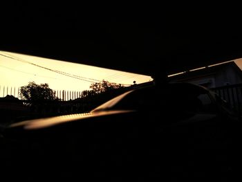 Silhouette trees by road against clear sky during sunset