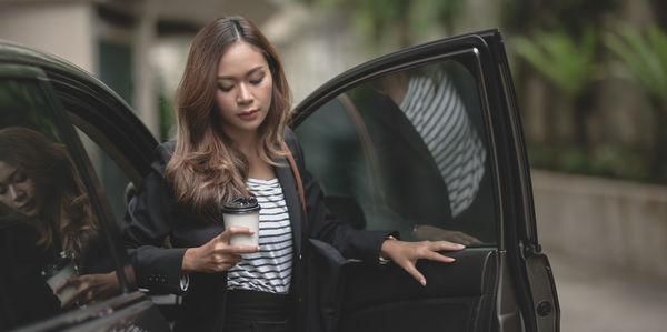 Young woman using phone while sitting in car