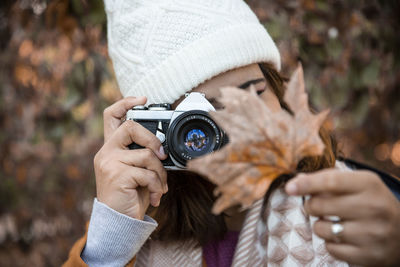 Woman photographing the typical maple leaf in autumn