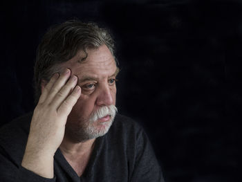 Close-up of depressed mature man against black background