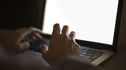 Close-up of cropped hands using laptop