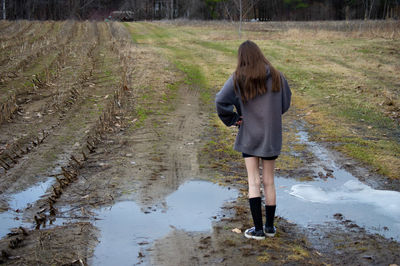 Rear view of girls standing on muddy land