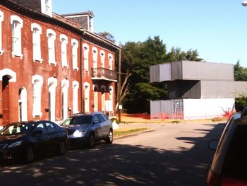 Cars on street by buildings in city against clear sky