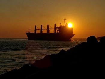 Silhouette ship in sea against sky during sunset