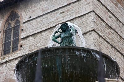 Low angle view of statue against fountain wall