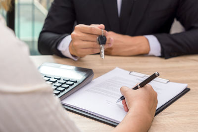 Cropped image of man holding paper with text on table