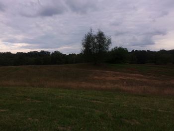 Scenic view of grassy field against cloudy sky