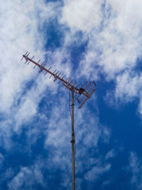 Low angle view of crane perching on pole against sky