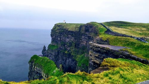 Scenic view of cliff by sea against sky