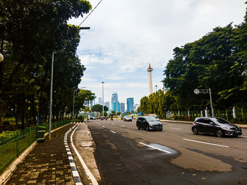 Cars on road in city against sky