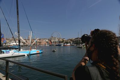 Rear view of woman in harbor by sea against sky