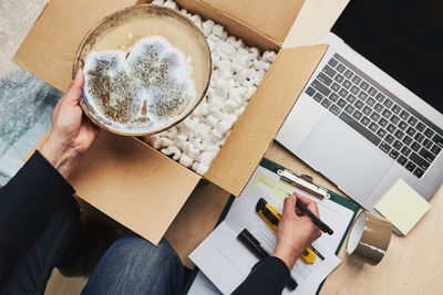 Business owner packing online order to delivery to customer. preparing parcel box with ceramic plate